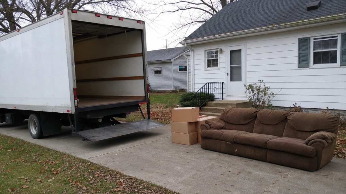 Junk removal truck loading an old couch in an Evansville Indiana driveway